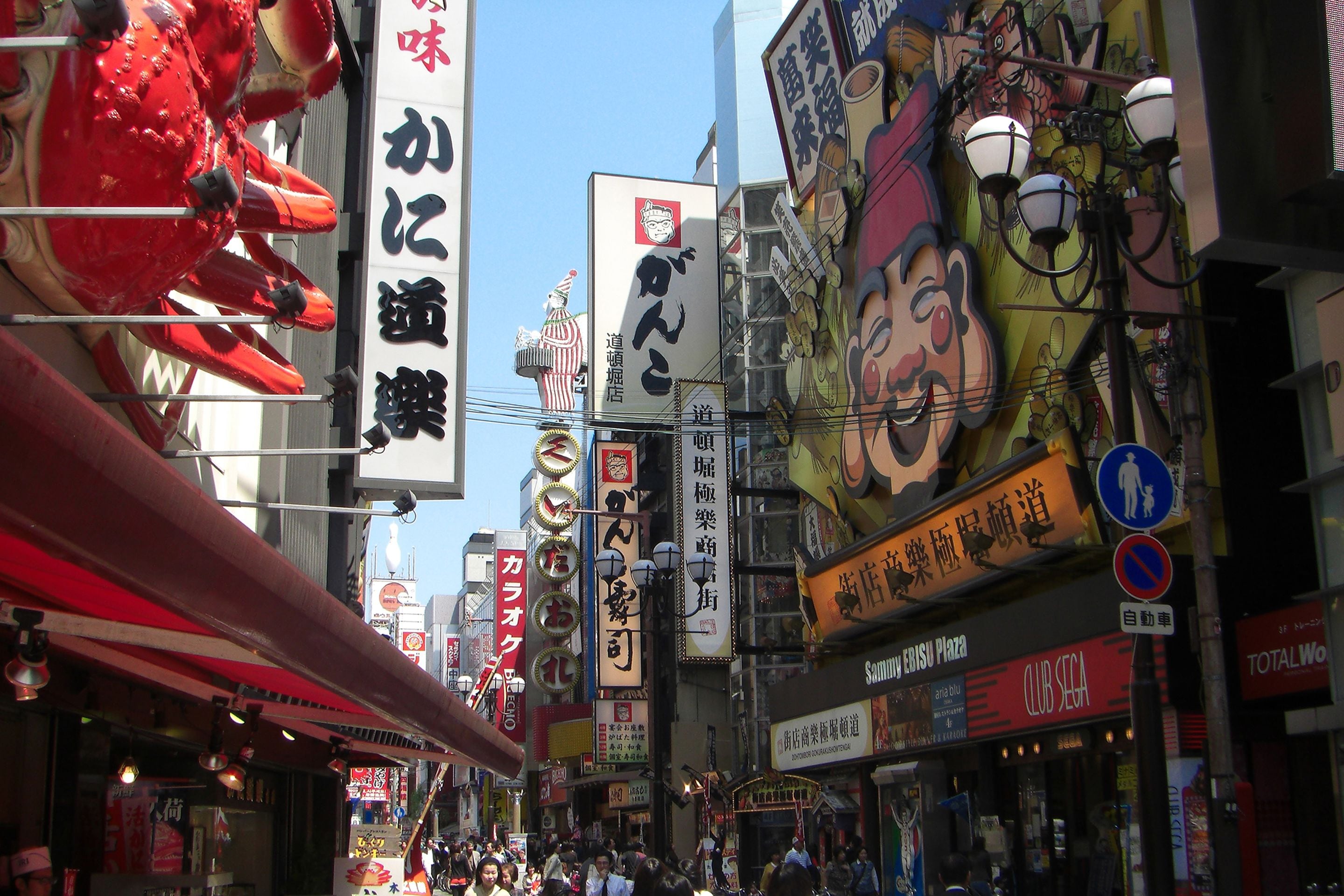 A busy urban street with various commercial signs and storefronts.