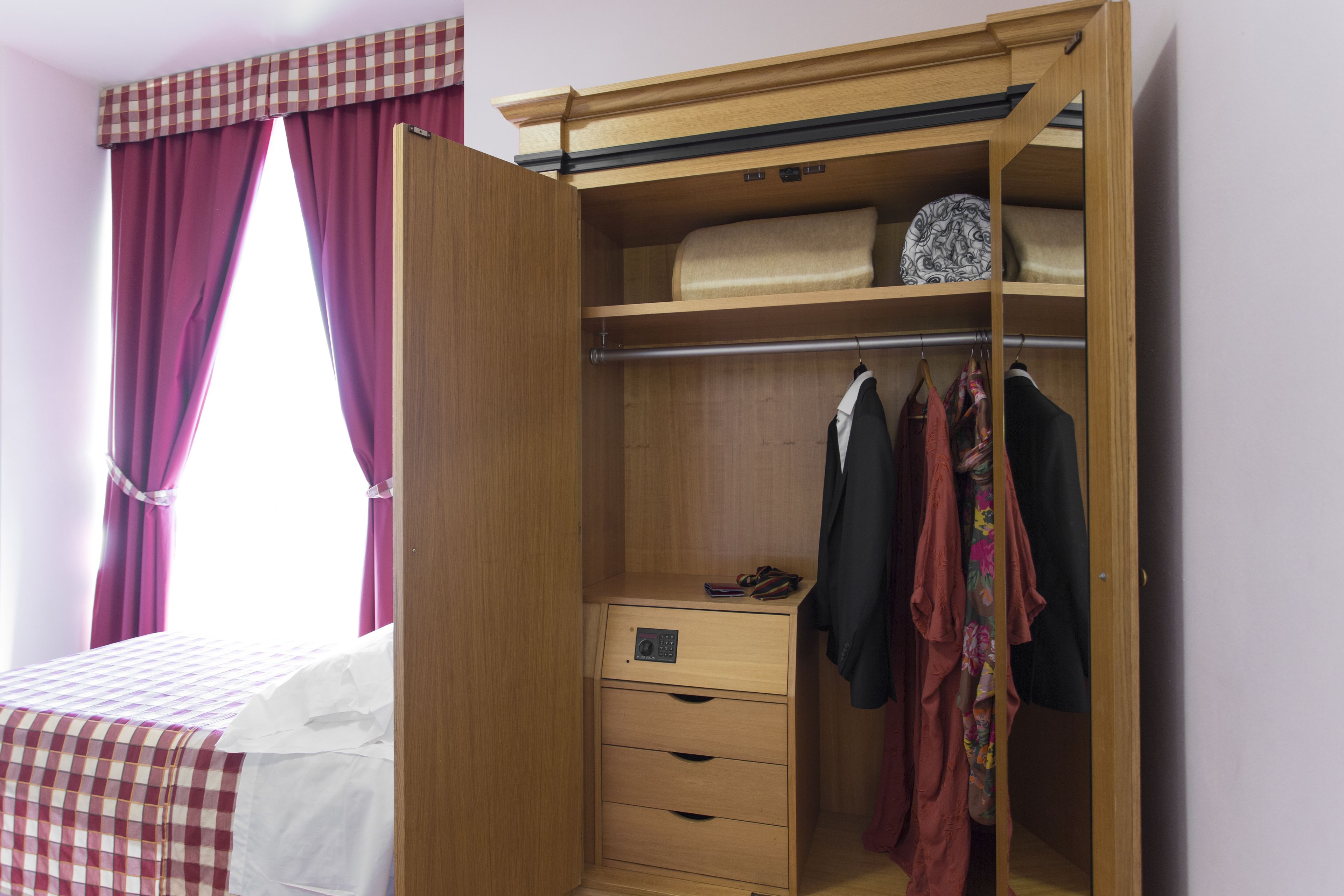 Un armario de madera con espejo plano, una barra para colgar ropa y un cajón pequeño.