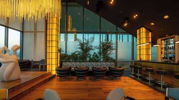 A modern interior with a bar area, seating with stools, and a stage.
