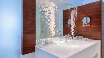 A modern bathroom with a large mirror, white sink, and wooden vanity.