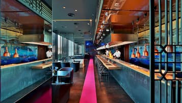 A modern restaurant with a long counter, bar seating, and a central walkway.
