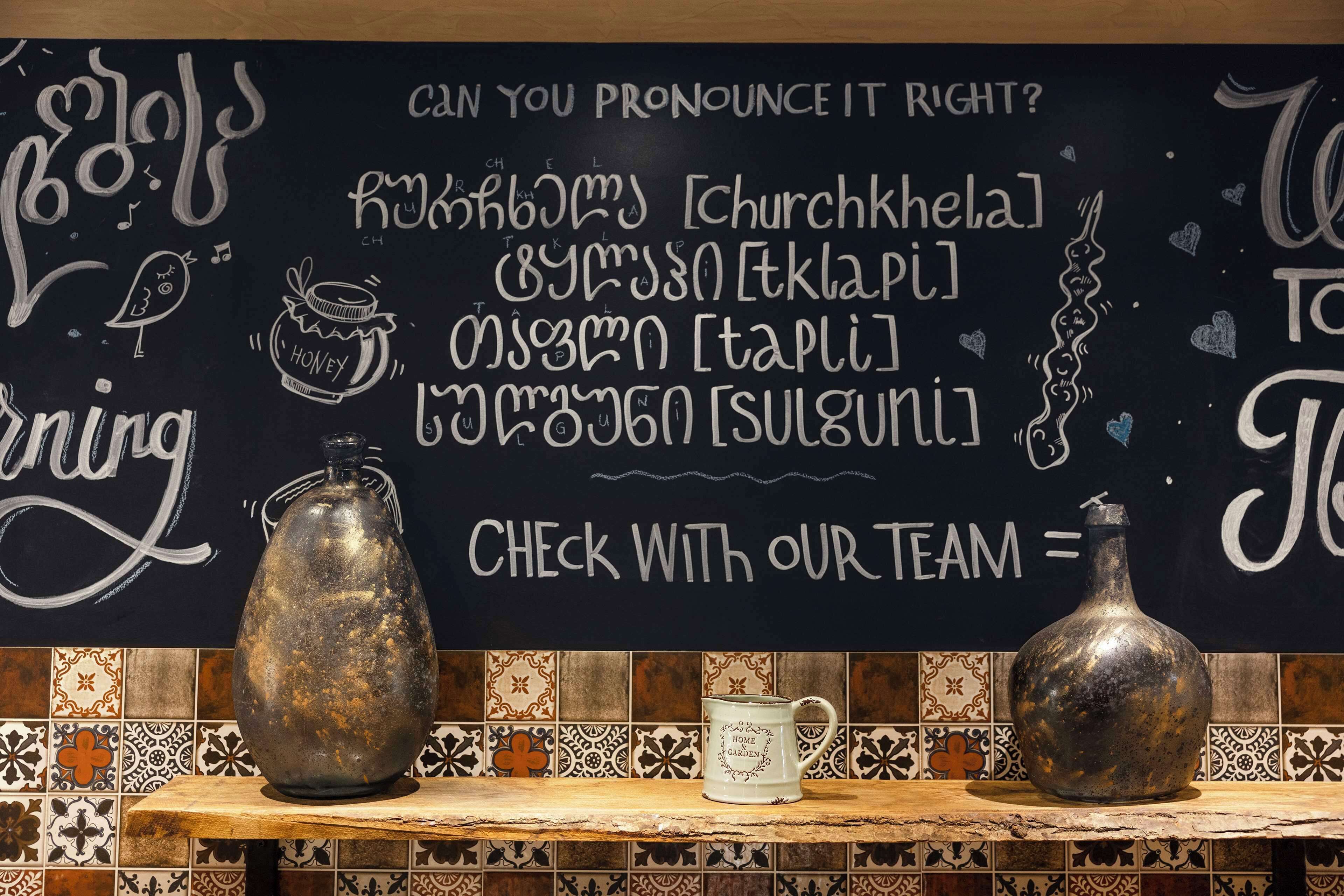 A chalkboard with language pronunciation tips and a decorative jar on a shelf.