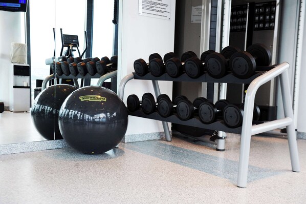A gym with a rack of dumbbells and exercise balls.