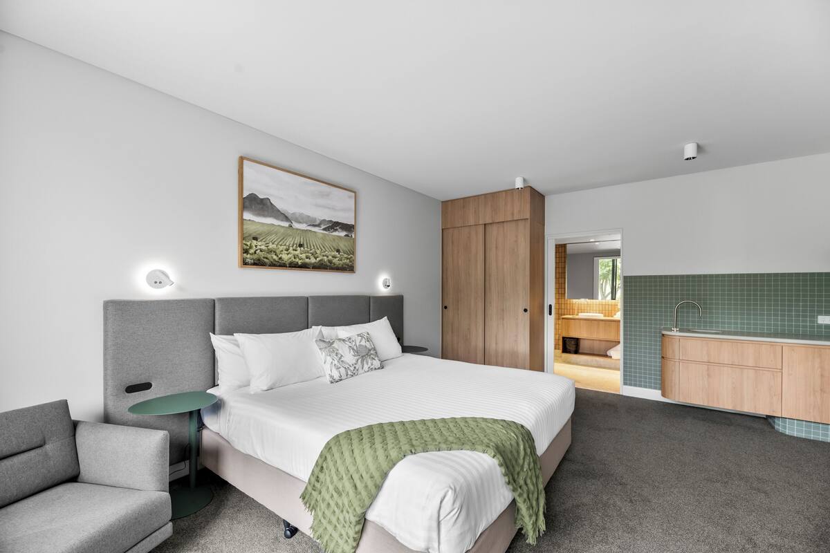 A modern bedroom with a bed, bedside table, and a green throw blanket.