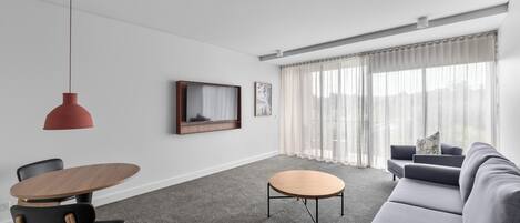 Una sala de estar moderna con un sofá gris, una mesa de centro redonda de madera y una silla negra.