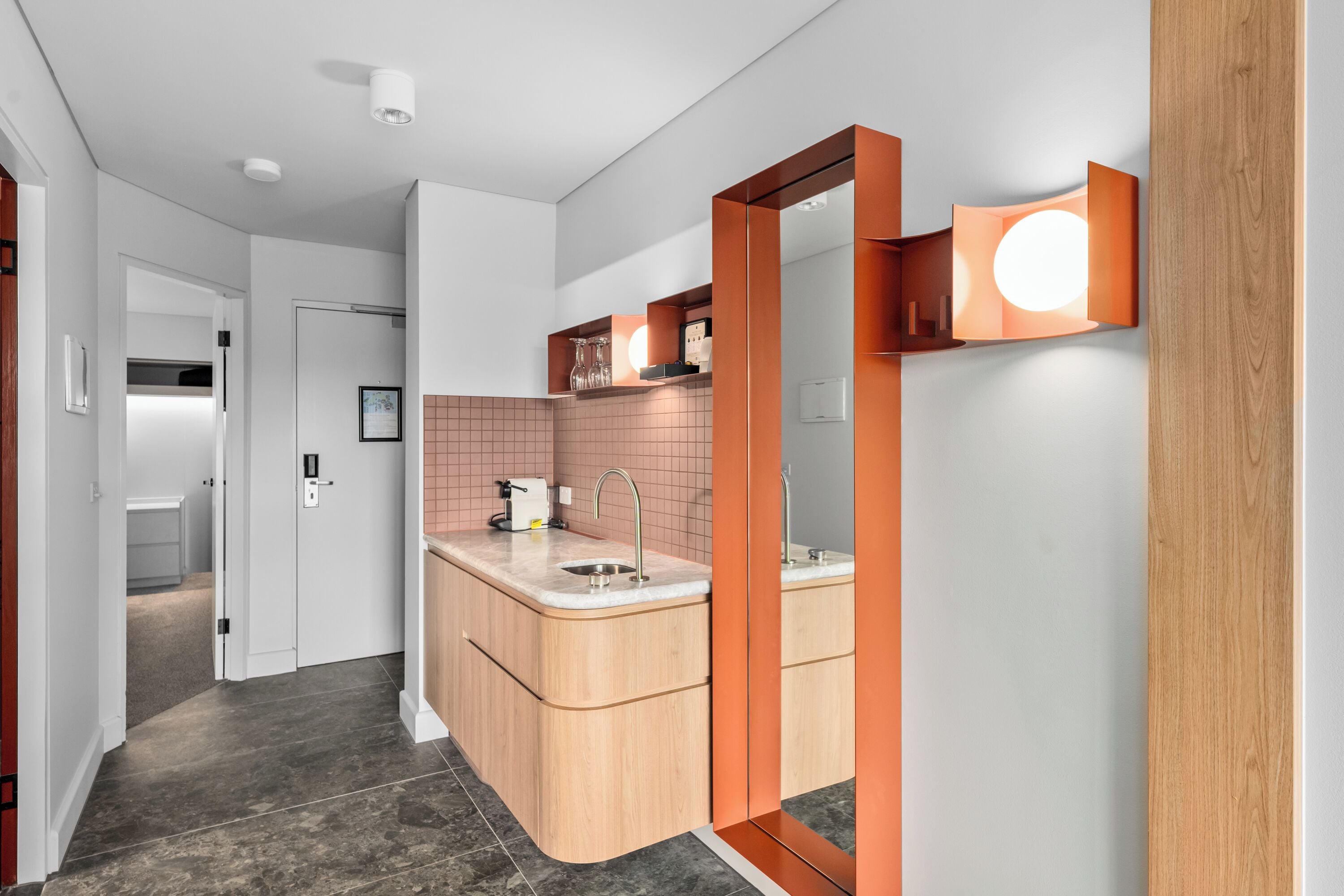 A modern bathroom with a curved sink, a mirror, and a light fixture.