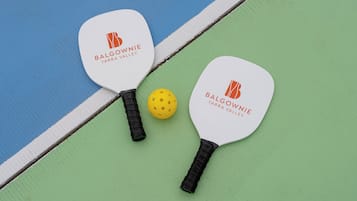 Dos palas de paddle con el logo "Balgownie Yarra Valley" y una pelota amarilla en una cancha.