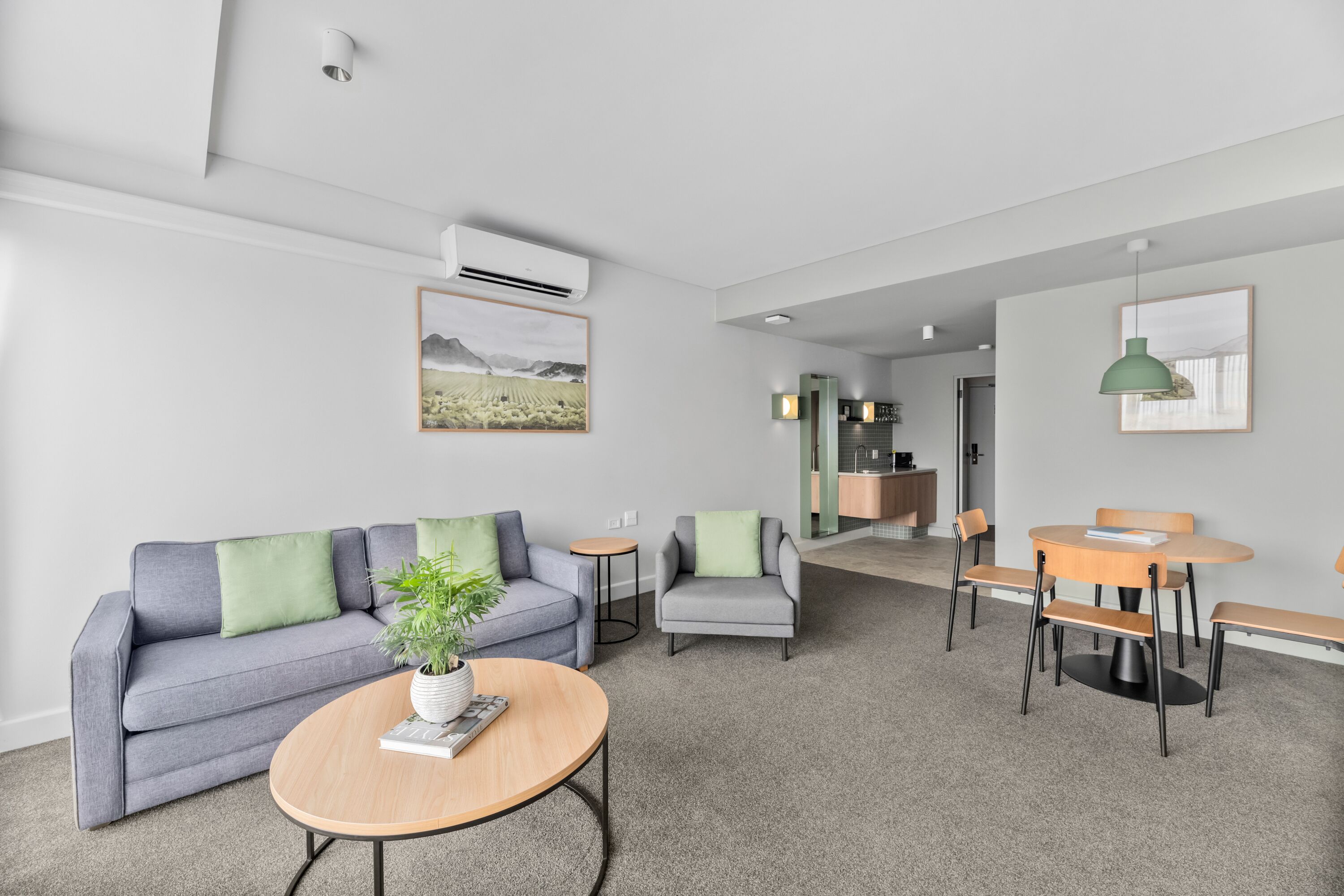 Una sala de estar moderna con un sofá gris, una mesa de centro redonda y una zona de comedor con mesa y sillas de madera.