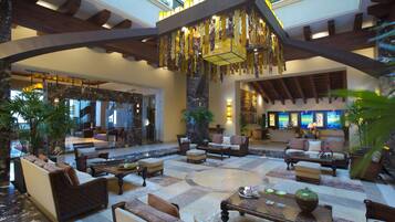 A spacious lobby with multiple seating areas, a reception desk, and a large chandelier.