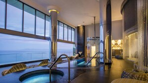 A spa area with two hot tubs, seating, and a view of the sea. - Garza Blanca Preserve Resort & Spa (Puerto Vallarta)