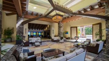 A spacious lobby with a high ceiling, wooden beams, and a central seating area with sofas and armchairs.