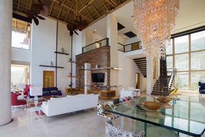 A spacious living area with a glass coffee table, modern furniture, and a large window offering a view of the outdoors.