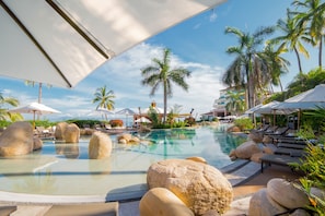 A resort pool area with lounge chairs, umbrellas, and palm trees. - Garza Blanca Preserve Resort & Spa (Puerto Vallarta)