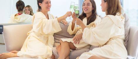 A group of people in robes sitting on a couch, toasting with champagne glasses.