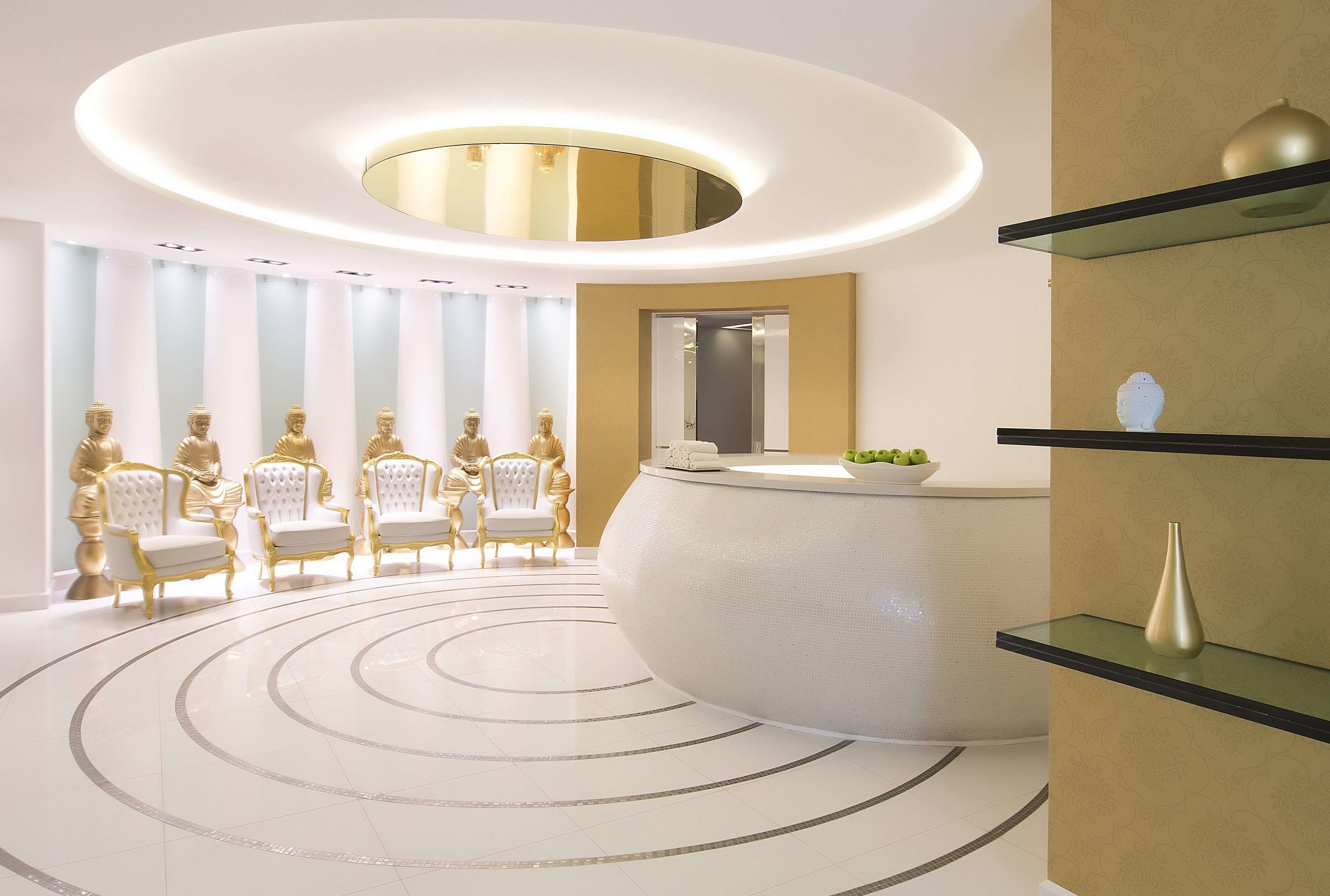Uma área de recepção com design de piso circular, balcão de recepção e cadeiras douradas.