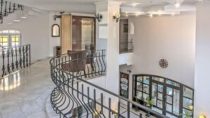 Ein großzügiger Innenraum mit einer geschwungenen Treppe, einem Balkon mit Geländer und einer modernen Deckenleuchte.