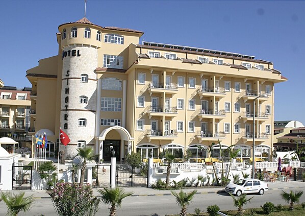 A multi-story hotel with a central tower, balconies, and a flag.