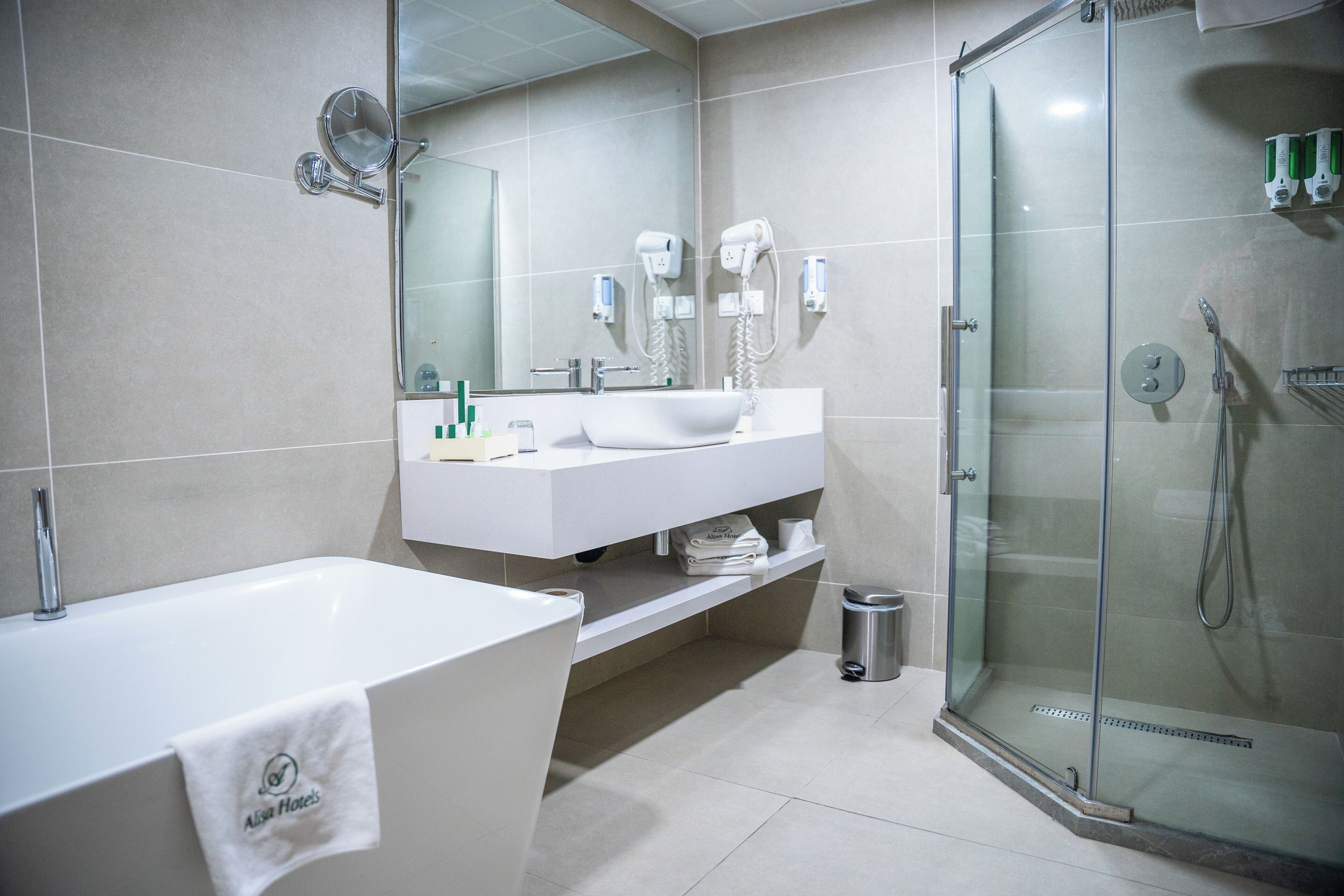 A modern bathroom with a bathtub, a glass-enclosed shower, a white sink, and a mirror.