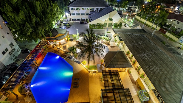 Ein Luftbild eines Hotels mit einem großen, blauen Pool, Sitzbereichen im Freien und einem gut beleuchteten Innenhof.