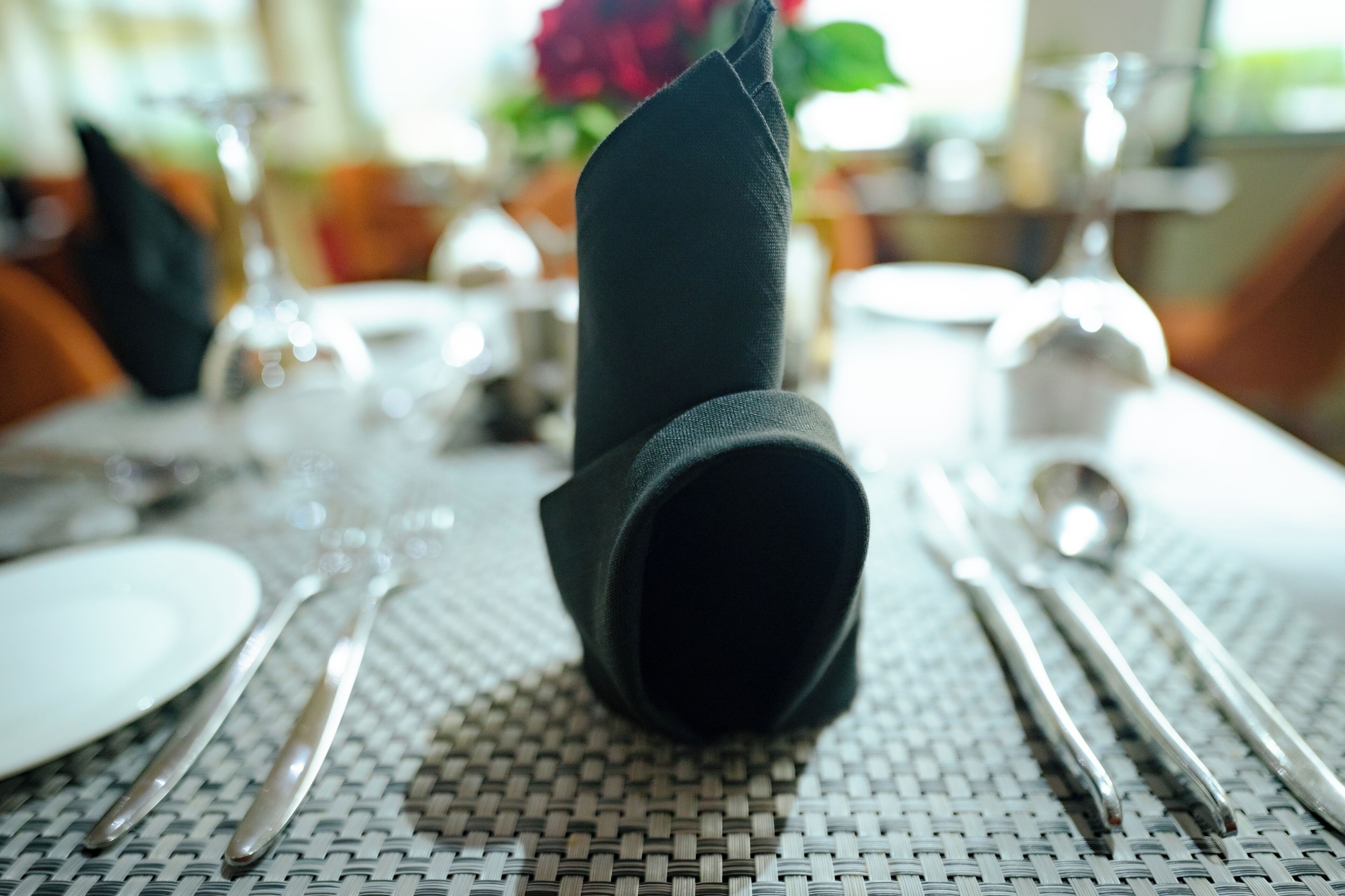 A table set with a folded napkin, silverware, and a white plate.