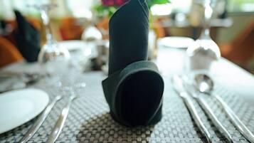 A table set with a folded napkin, silverware, and a white plate.