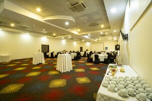 A conference room with round tables, chairs, and a buffet table with dishes.