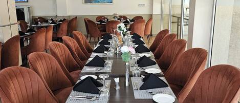 A conference room with a long table, brown upholstered chairs, and a modern ceiling design.