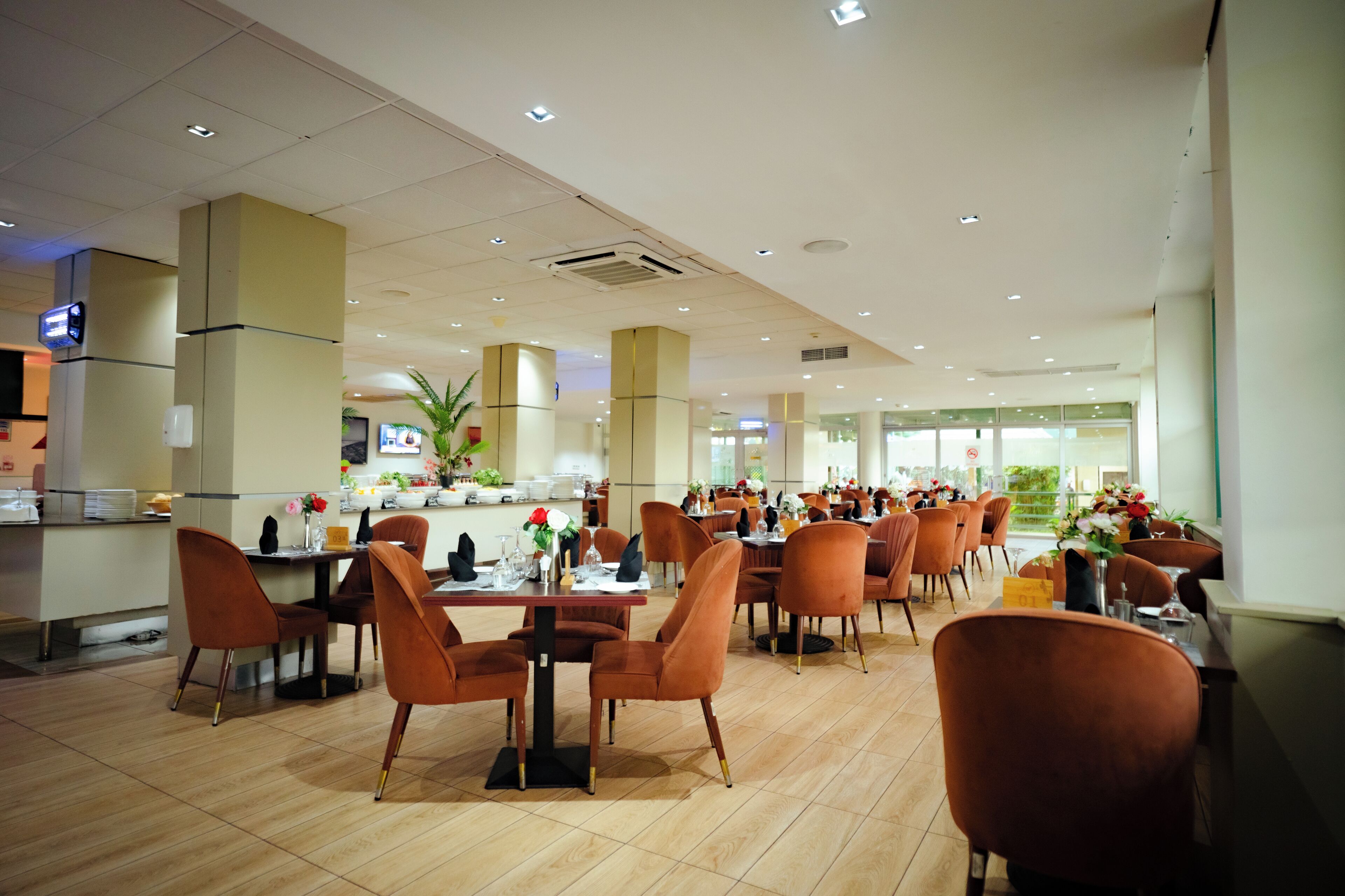 Un restaurante espacioso con techos altos, iluminación moderna y diversas opciones de asientos.