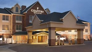 Un hôtel Country Inn & Suites avec une façade en briques, une entrée couverte et un drapeau américain.