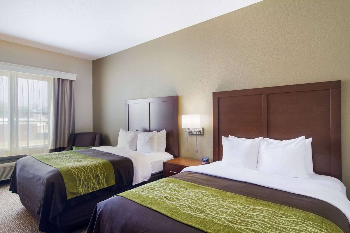 A hotel room with two beds, a desk, and a chair.