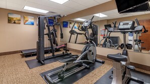 Un gimnàs amb diferents aparells d'exercici, incloent cintes de córrer, una bicicleta estatica i aparells de musculació.