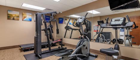 Une salle de sport équipée de divers appareils d’exercice, notamment des tapis de course, un vélo d’appartement et des appareils de musculation.