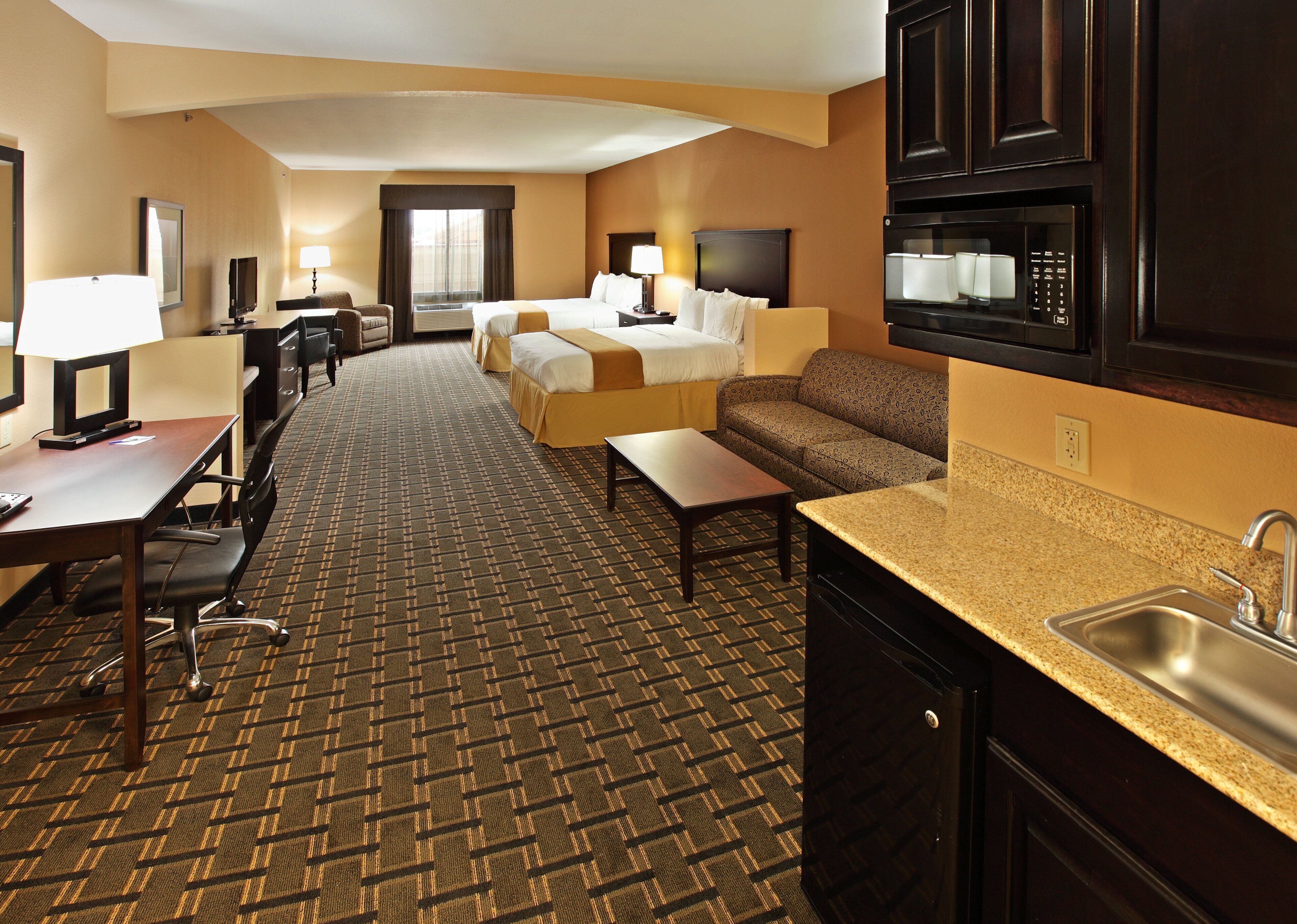 Habitación de hotel con cama, sofá, escritorio y kitchenette.