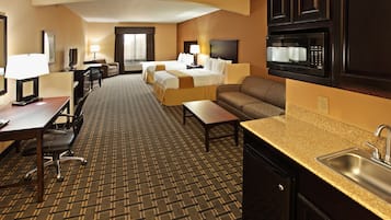 Habitación de hotel con cama, sofá, escritorio y kitchenette.