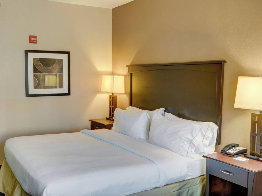 A hotel room with a large bed, two bedside tables, a lamp, a phone, and a framed picture on the wall.