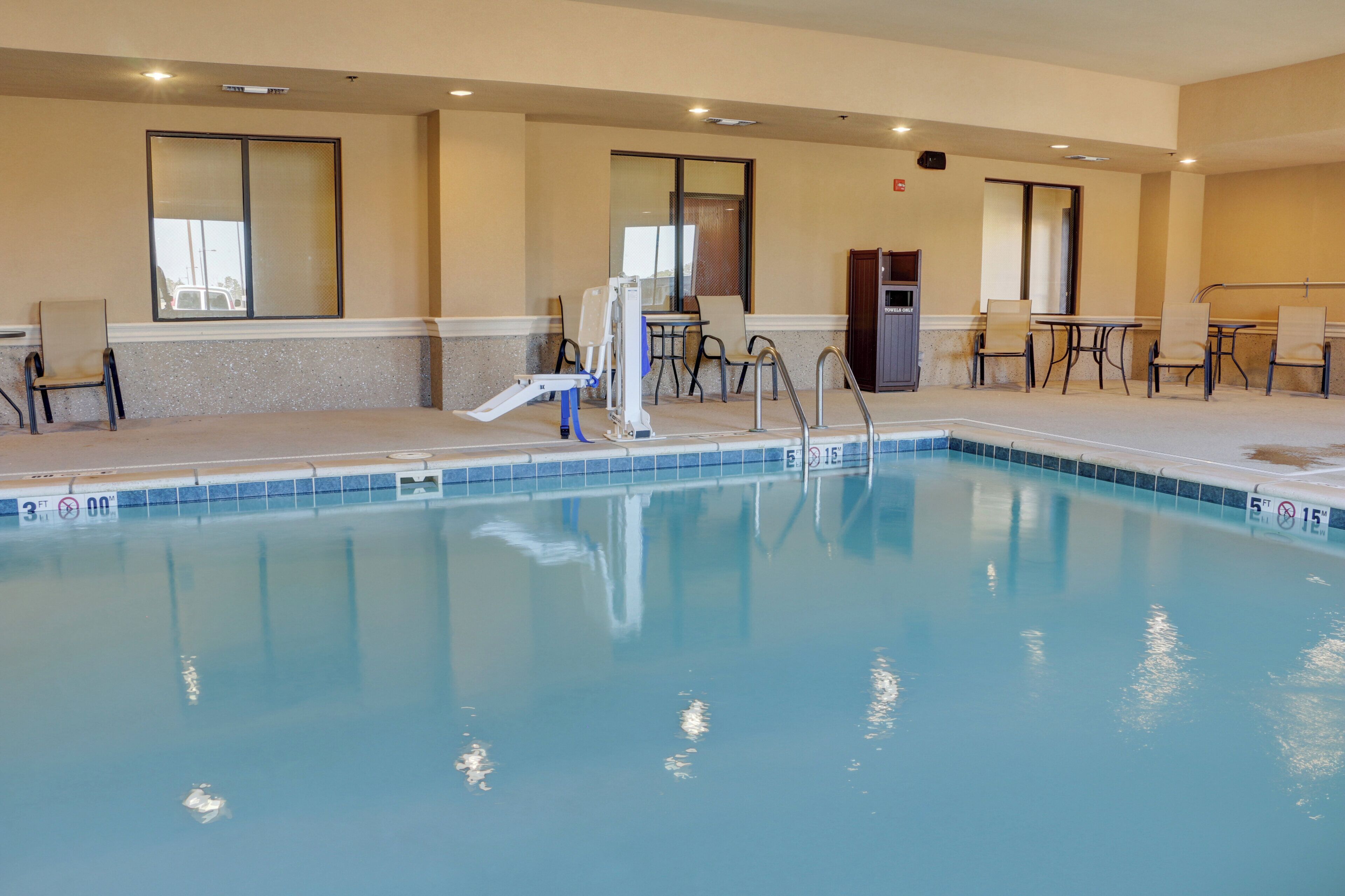 A pool area with a lifeguard chair, a pool ladder, and a seating area with tables and chairs.