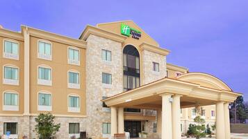 A Holiday Inn Express & Suites hotel with a stone facade, multiple windows, and a covered entrance.