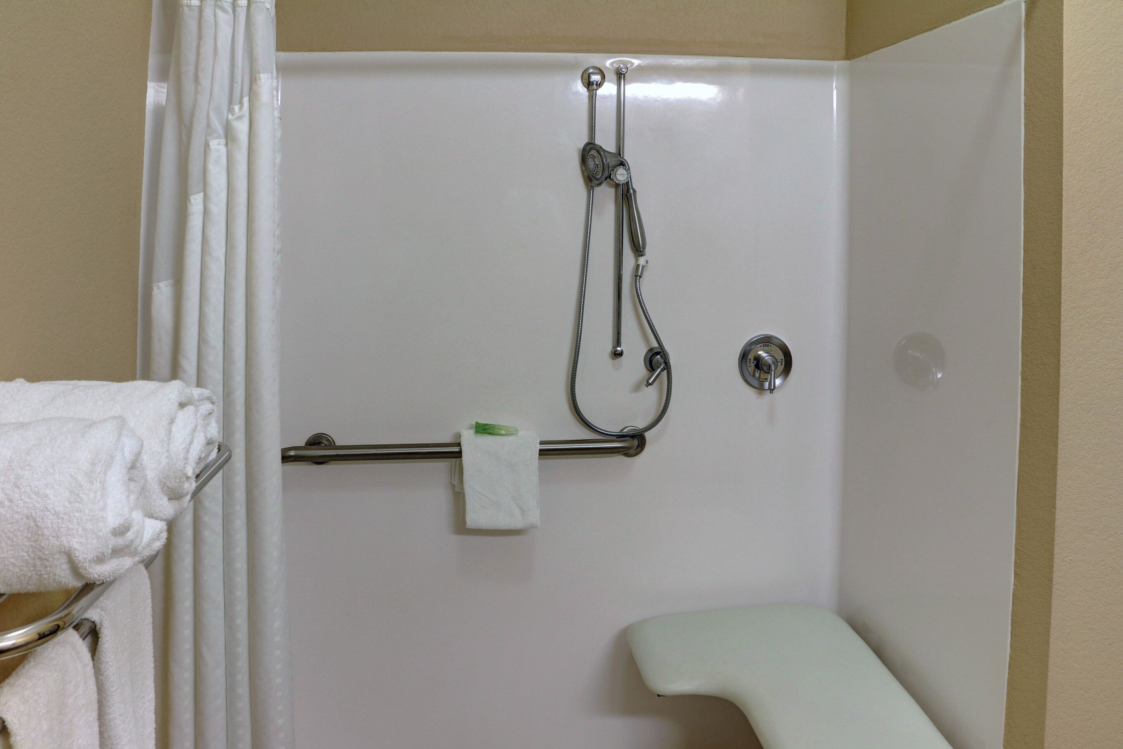 A shower area with a handheld showerhead, a towel rack with a folded towel, and a toilet.