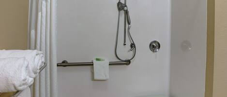 A shower area with a handheld showerhead, a towel rack with a folded towel, and a toilet.