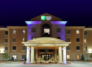 Un hôtel Holiday Inn Express & Suites doté d’une façade symétrique, de grandes colonnes à l’entrée et surplombant un ciel dégagé.