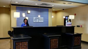 Un comptoir d’accueil d’un hôtel Holiday Inn Express, avec un logo bleu et blanc, deux comptoirs d’accueil noirs et un aménagement intérieur moderne.