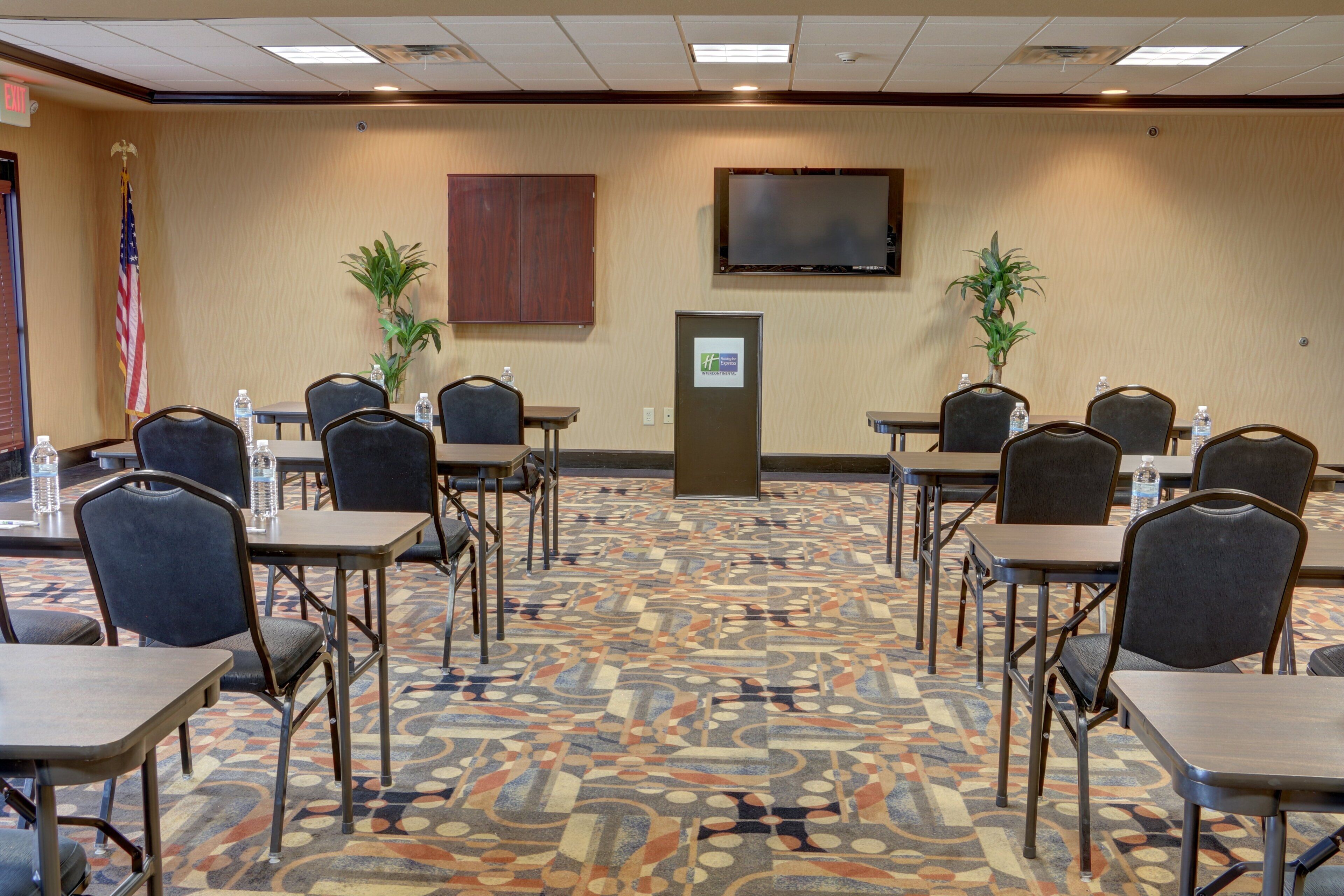 A conference room with a patterned carpet, multiple tables, and chairs.