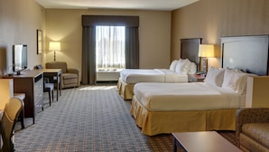 A hotel room with two beds, a desk with a chair, a television, and a window with curtains.