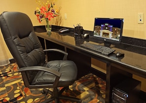 Un mostrador de recepción de hotel con una computadora, un teléfono y un jarrón de flores.