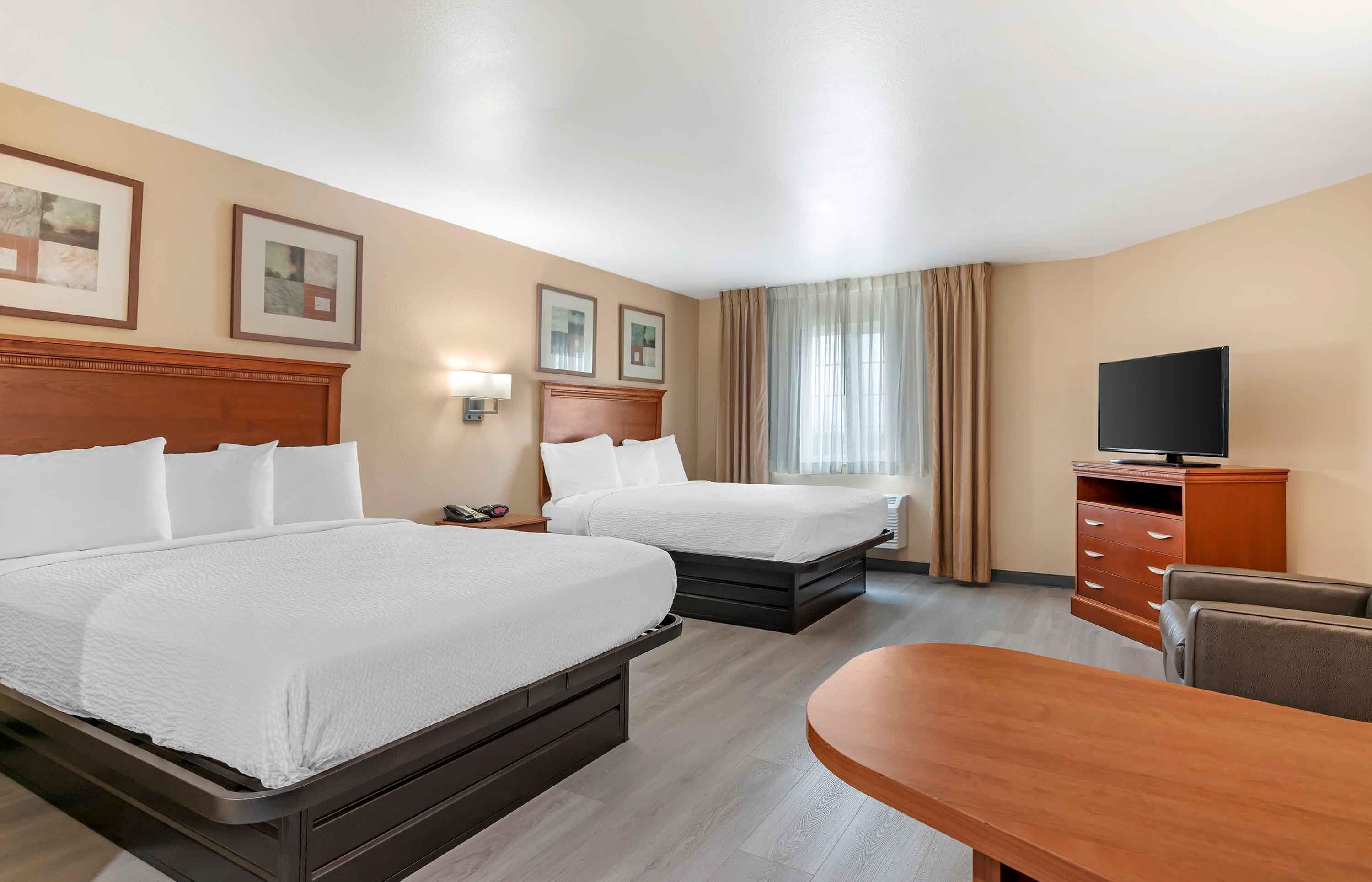 Habitación de hotel con dos camas, televisión, escritorio y una silla.