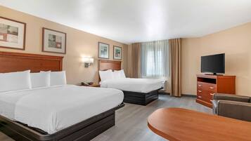 Habitación de hotel con dos camas, televisión, escritorio y una silla.