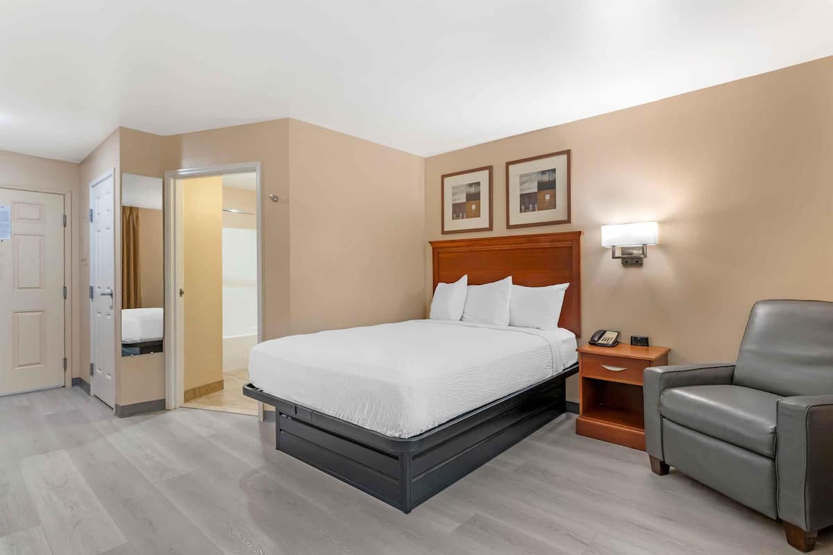 Ein Hotelzimmer mit einem Bett, einem Sessel, einem Nachttisch und einer Wandleuchte.