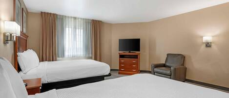 A hotel room with two beds, a TV, a desk, and a chair.