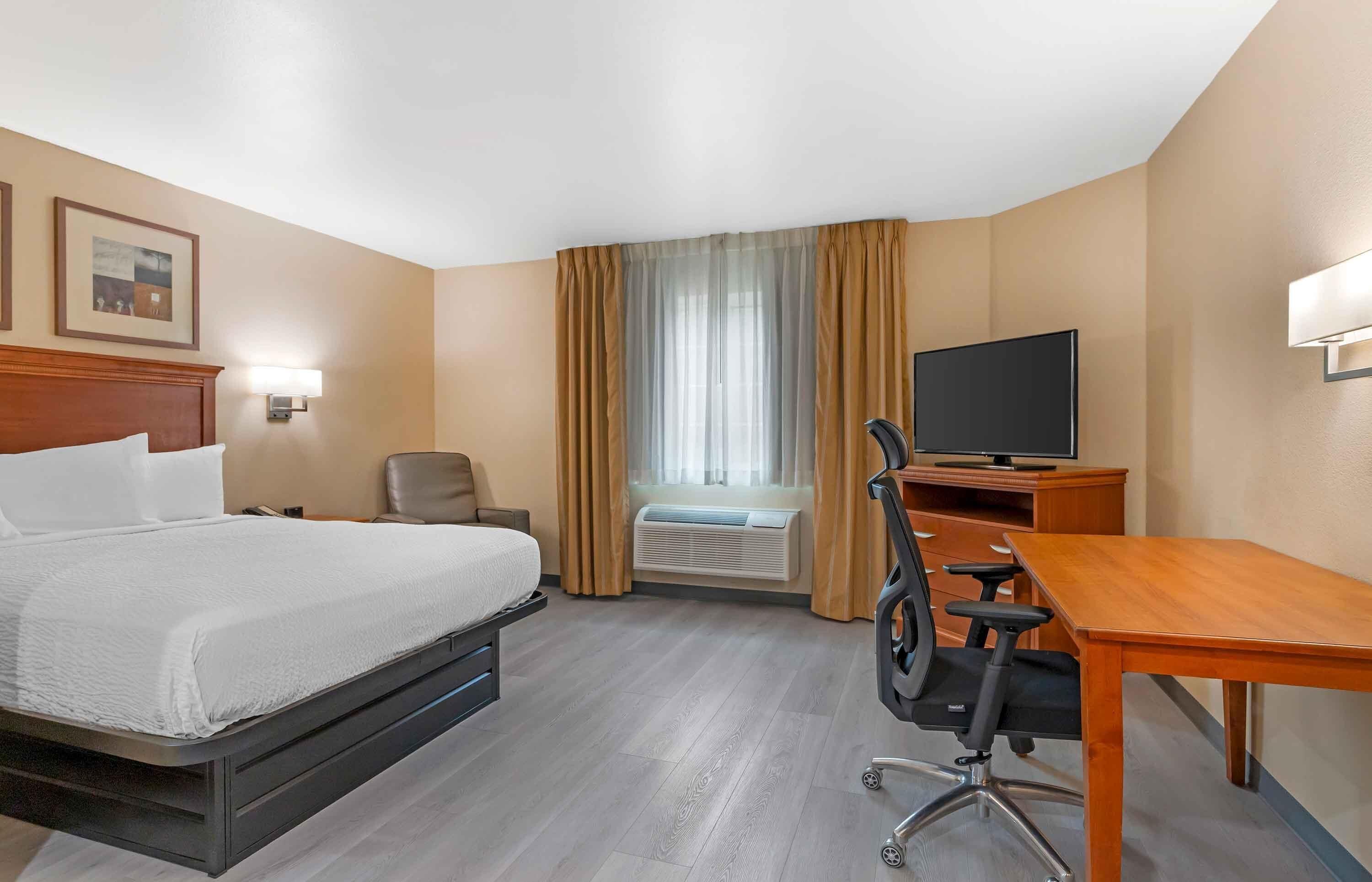 Habitació d'hotel amb llit, escriptori, cadira, televisió i aire condicionat.