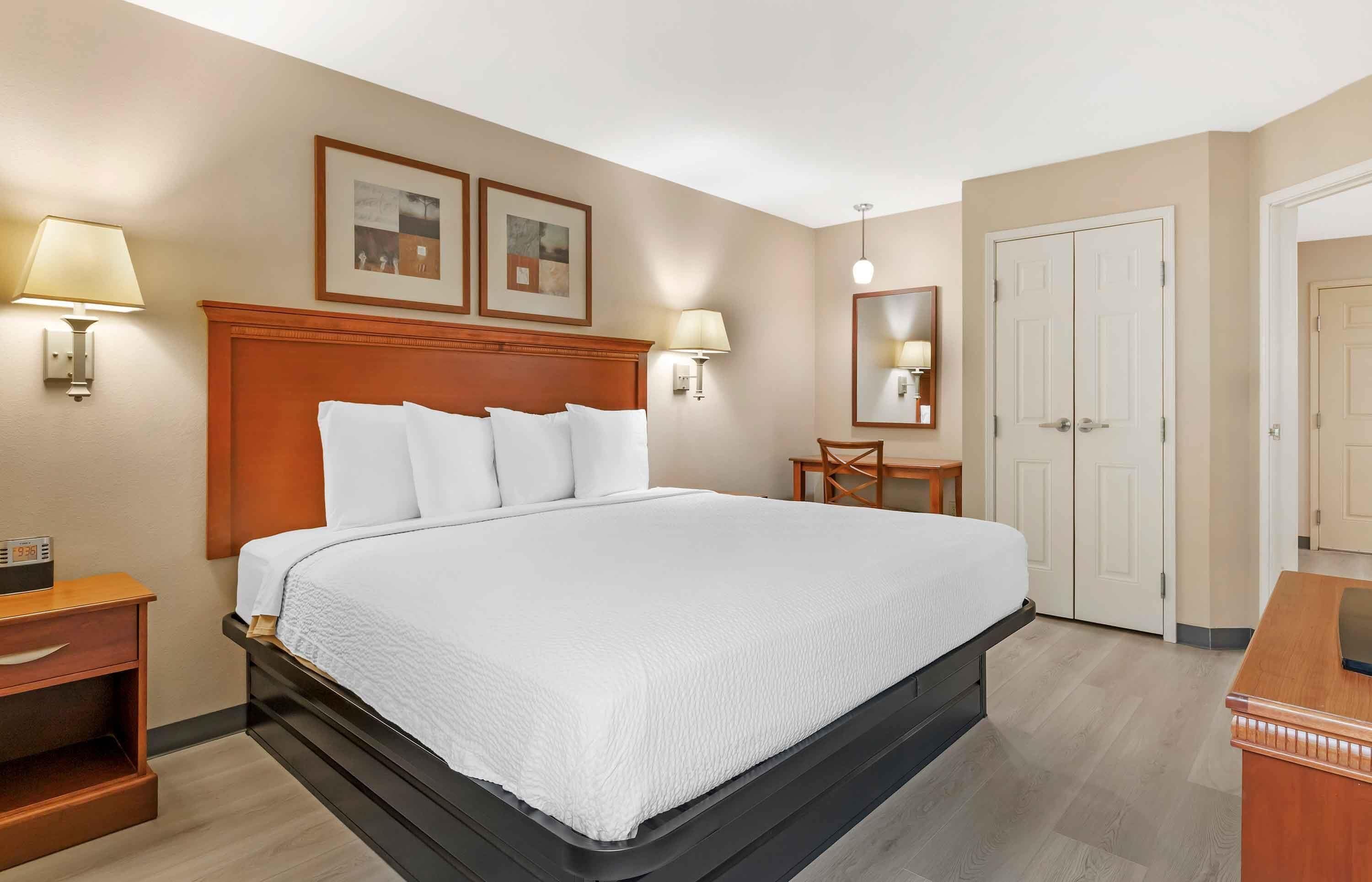 Una habitación de hotel con una cama grande, mesitas de noche, un escritorio y un armario.